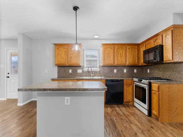 a kitchen with stainless steel appliances granite countertop a stove a sink and a microwave