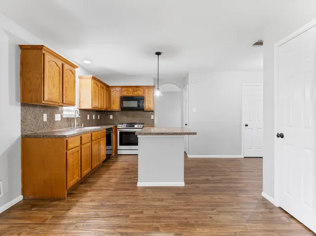 a kitchen with kitchen island granite countertop a sink cabinets and stainless steel appliances