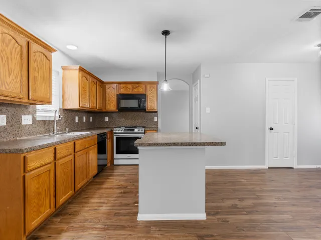 a kitchen with stainless steel appliances granite countertop a stove a sink and a microwave