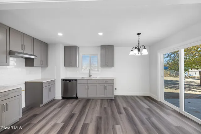 an empty room with wooden floor fireplace and windows