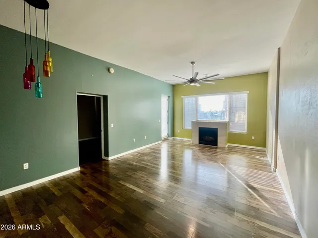 a view of empty room with wooden floor and fan