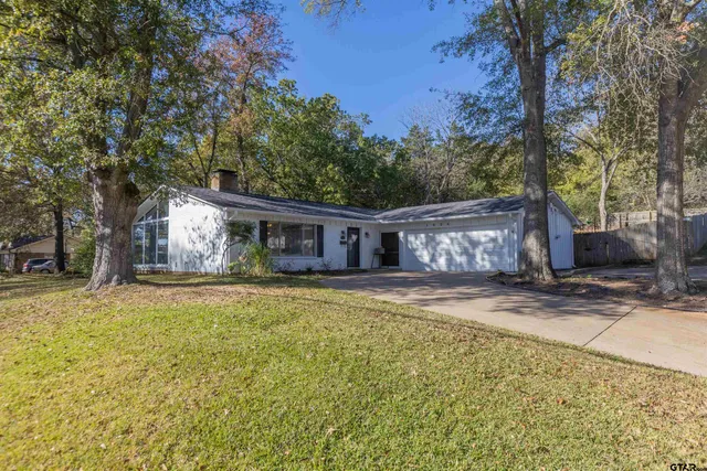 a front view of a house with a garden and trees