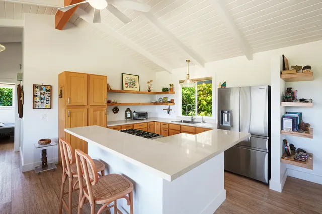 a kitchen with stainless steel appliances a stove a refrigerator a sink a dining table and chairs with wooden floor