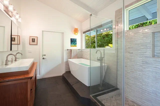 a bathroom with a sink a bathtub and next to a window