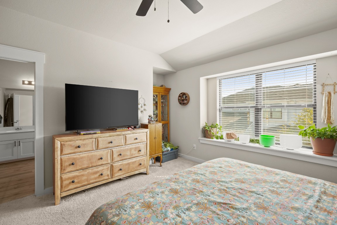 195 C Waterside Road Buda, TX 78610 - Photo 22 of 27 Bedroom featuring lofted ceiling, light colored carpet, ceiling fan, and ensuite bath