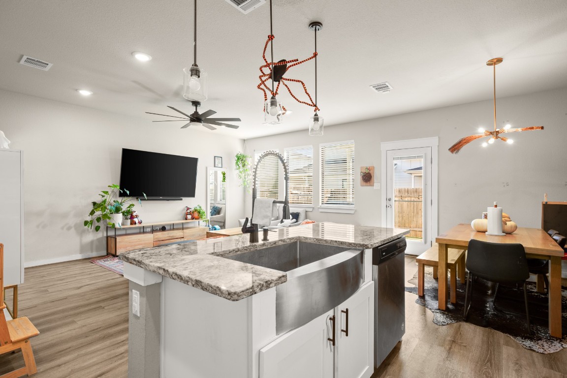 195 C Waterside Road Buda, TX 78610 - Photo 9 of 27 Kitchen with light stone counters, white cabinetry, a kitchen island with sink, decorative light fixtures, and light wood-style floors