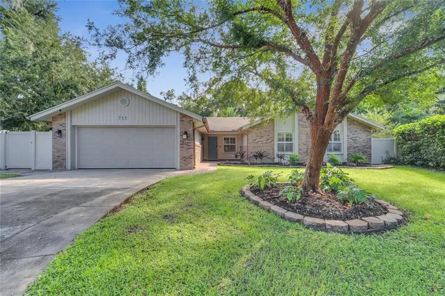 a view of a house with a yard and large tree