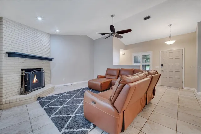 a living room with furniture a fireplace and a ceiling fan