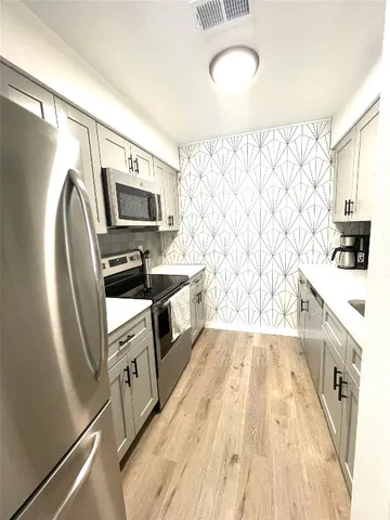 a kitchen with stainless steel appliances a stove a sink a microwave a refrigerator a sink and dishwasher