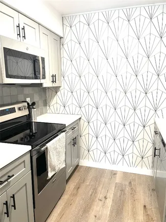 a kitchen with stainless steel appliances a stove a microwave and white cabinets