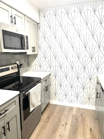 a kitchen with stainless steel appliances a stove a microwave and white cabinets