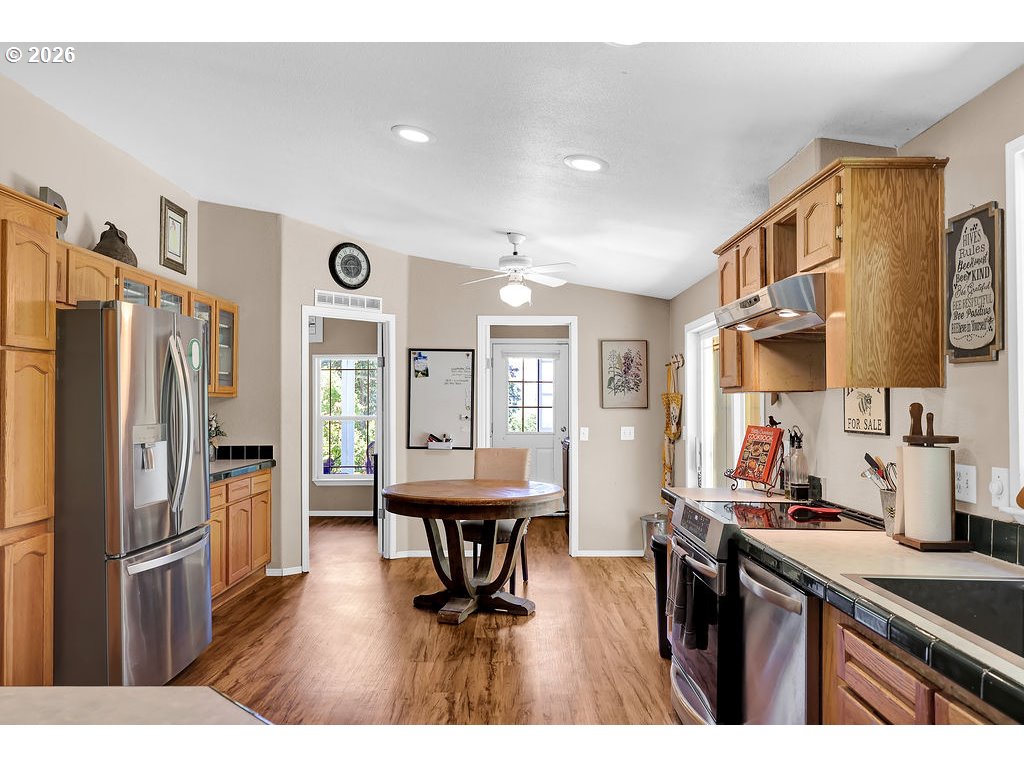 35235 Row River Road Cottage Grove, OR 97424 - Photo 14 of 28 a open kitchen with stainless steel appliances granite countertop a refrigerator a sink dishwasher a dining table and chairs with wooden floor