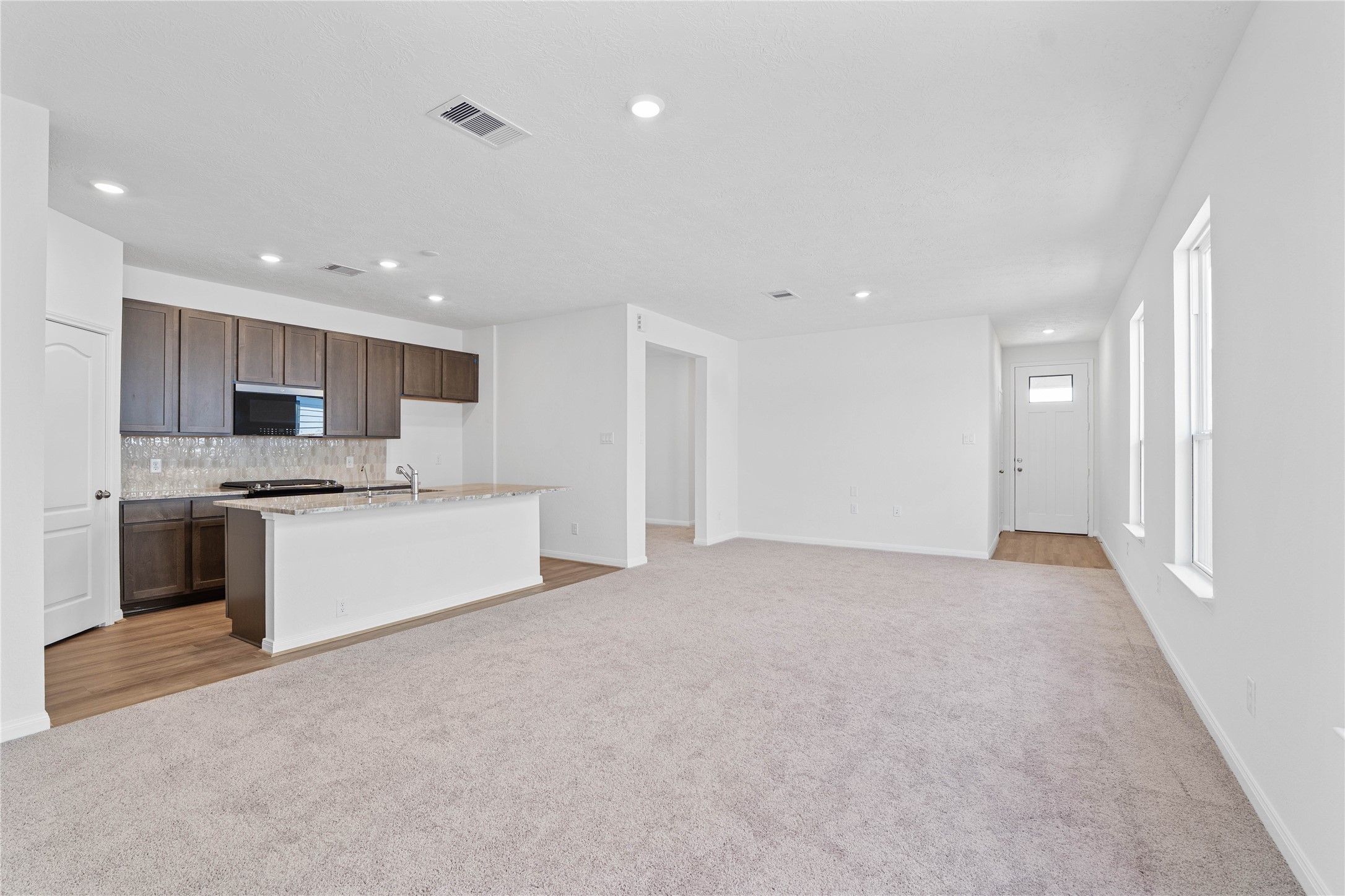 6423 Kentfield Drive Rosharon, TX 77583 - Photo 12 of 26 Designed for comfort and connection, this spacious open-concept great room boasts soaring ceilings, large windows with blinds, recessed lighting, and French Oak vinyl plank flooring, seamlessly merging with the stunning kitchen for easy living and entertaining.