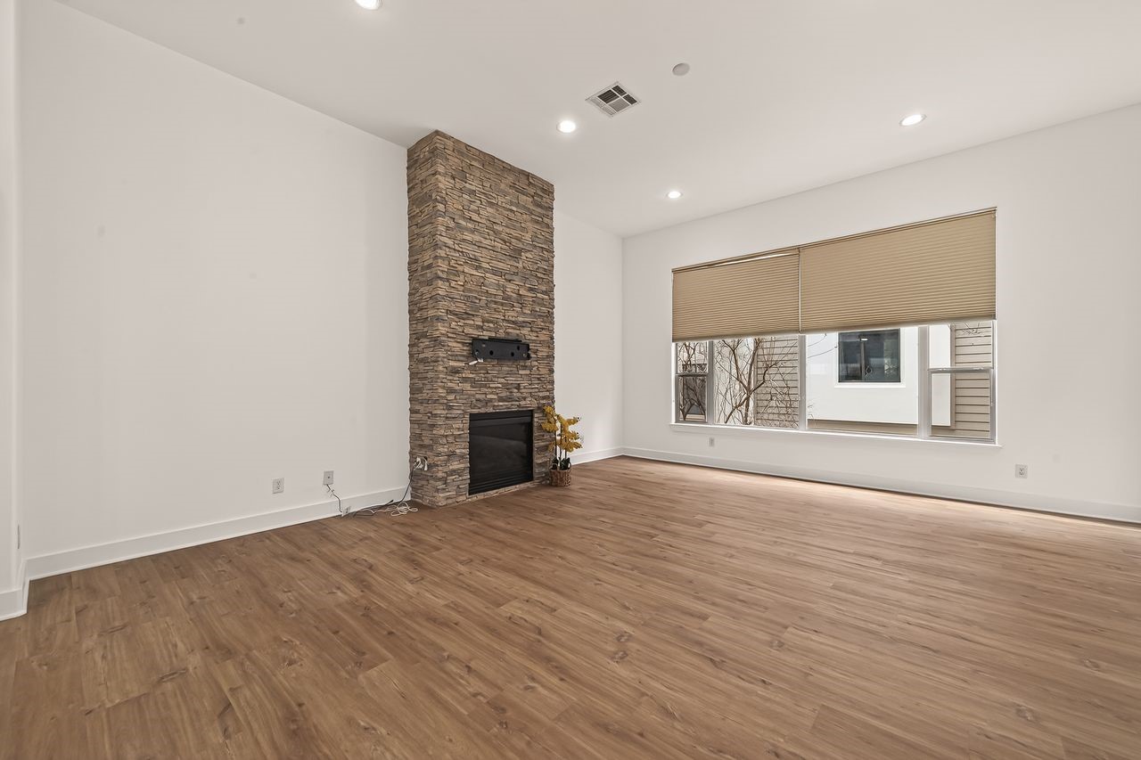 724 Ruthven Street Houston, TX 77019 - Photo 24 of 45 an empty room with wooden floor fireplace and windows