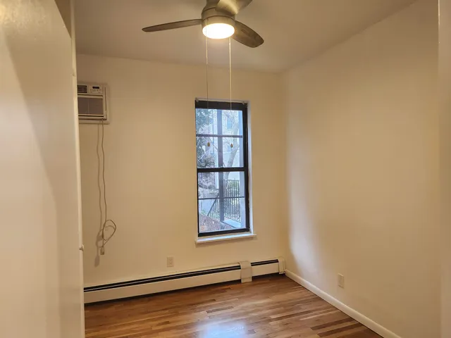 an empty room with wooden floor cabinet and windows
