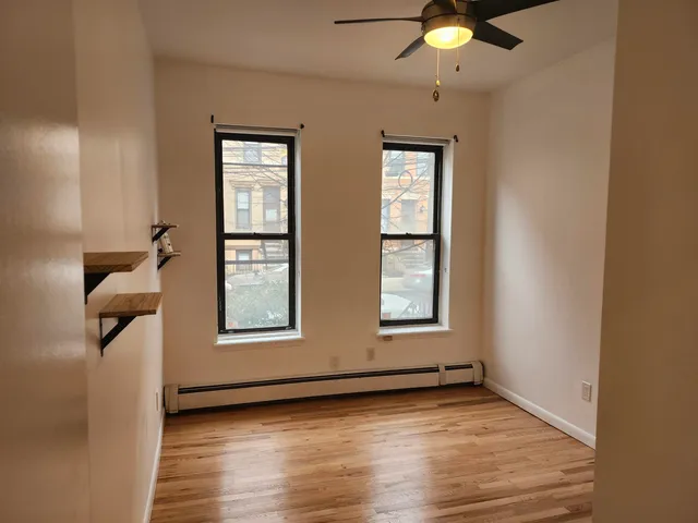 a view of an empty room with a window and wooden floor