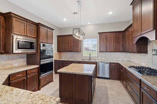 a kitchen with stainless steel appliances granite countertop a refrigerator a stove a sink and a microwave