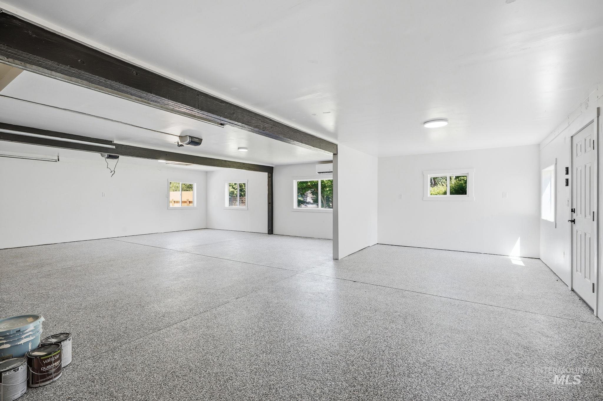 2152 Artesian Road Eagle, ID 83616 - Photo 36 of 50 Spacious utility room featuring a speckled epoxy floor, white walls, multiple windows, and exposed structural beams