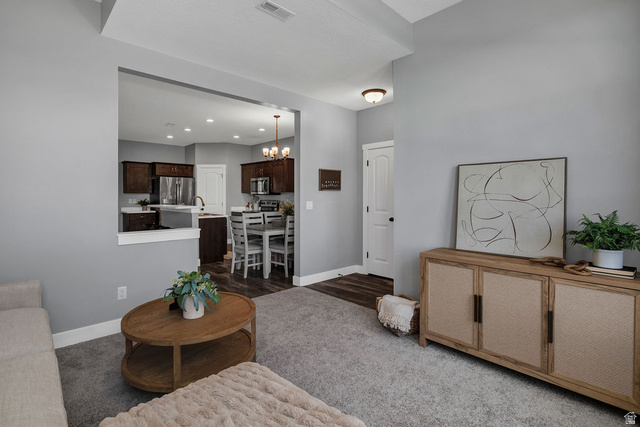 2483 South 1296th Street West Logan, UT 84321 - Photo 5 of 45 Expansive carpeted living area featuring light gray walls, an architectural cut-out providing an open feel to the kitchen and dining area, a white interior door, and recessed lighting