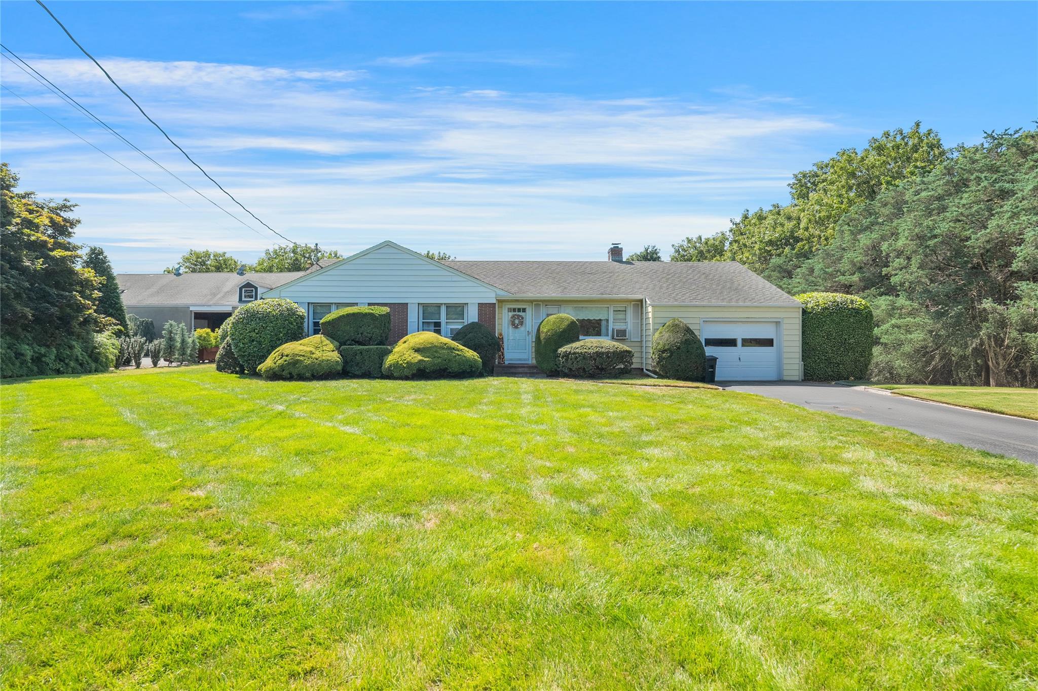 Ranch-style house with aphalt driveway, a front yard, and an attached garage