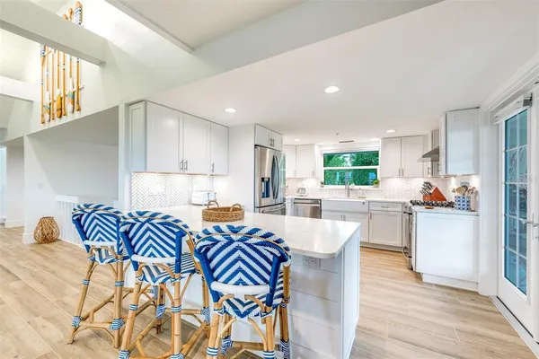 a kitchen with stainless steel appliances kitchen island granite countertop a sink and a refrigerator