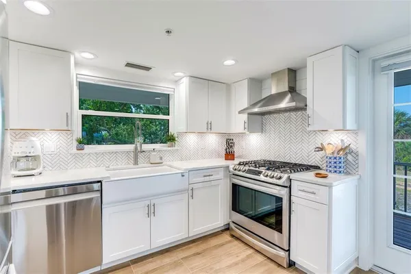 a kitchen with white cabinets stove and sink