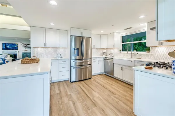a kitchen with stainless steel appliances granite countertop a refrigerator sink and white cabinets