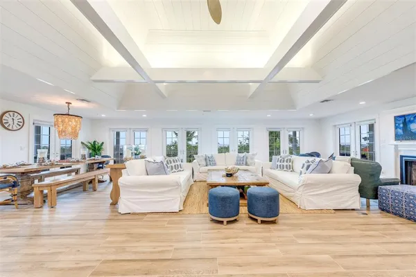 a living room with furniture large windows and wooden floor