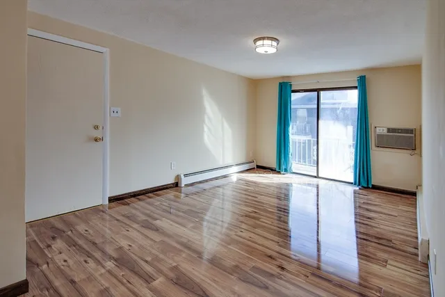 a view of an empty room with wooden floor and a window