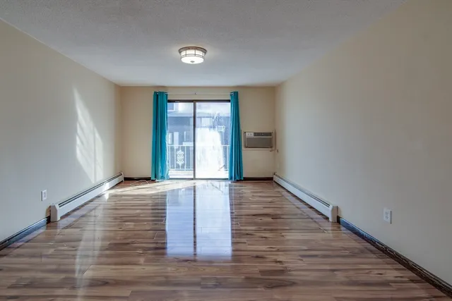 a view of an empty room with window and wooden floor