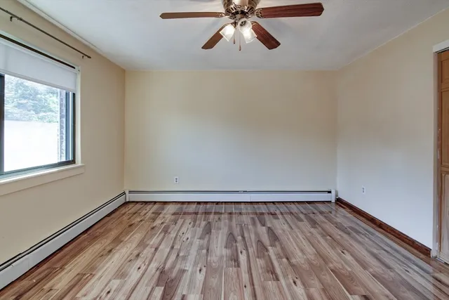 a view of a room with wooden floor fan and windows