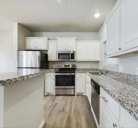 a kitchen with granite countertop a sink dishwasher a stove and a refrigerator