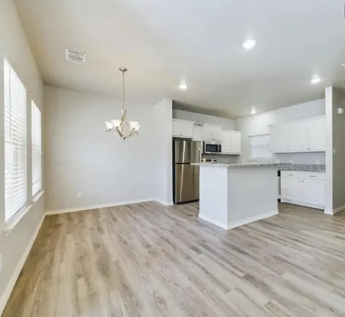 a view of a room with wooden floor fridge and a window