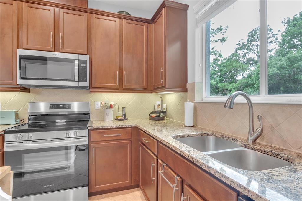 306 Reed Grass Drive Oviedo, FL 32765 - Photo 7 of 33 a kitchen with granite countertop a sink stove and cabinets