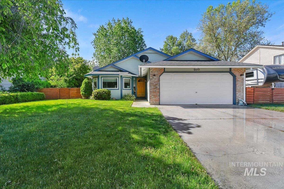 9215 West Preece Street Boise, ID 83704 - Photo 1 of 22 Single-story residence featuring a two-car garage, brick accents, a light blue exterior, and a wood privacy fence