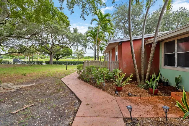 a view of a backyard with potted plants and large trees