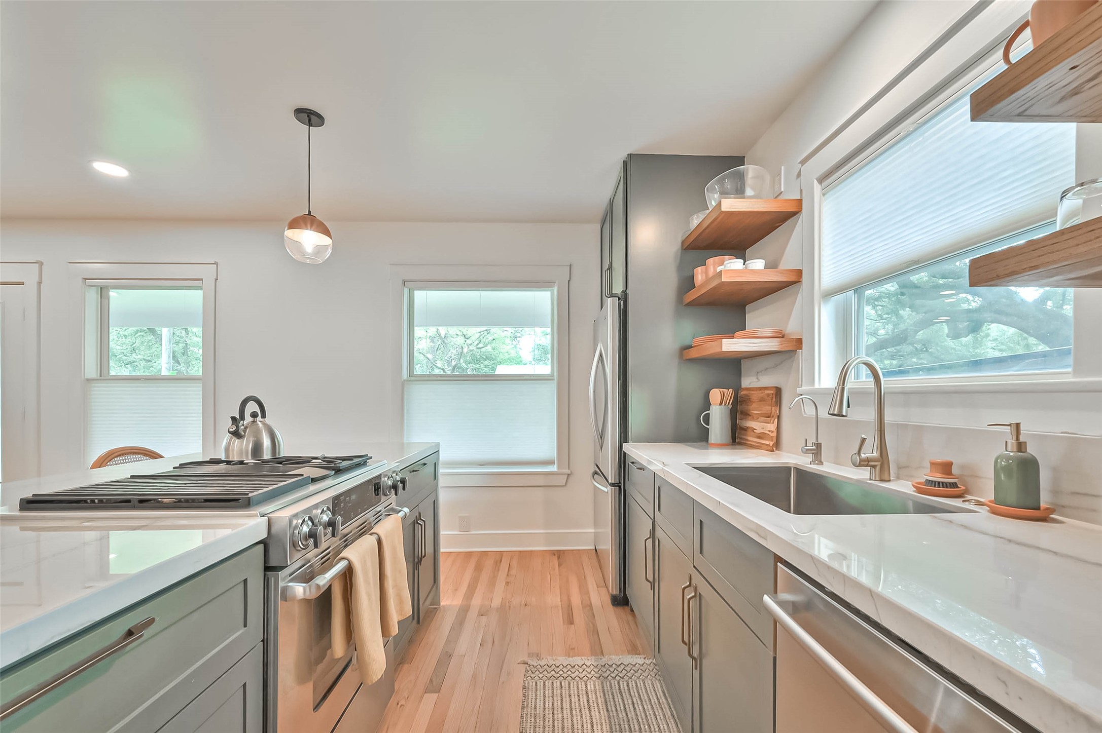 412 Sue Street Houston, TX 77009 - Photo 4 of 19 Another shot of the bright open kitchen, featuring sleek countertops, stainless steel appliances, and open shelving. Large windows provide plenty of natural light, and the wood flooring adds a warm touch.