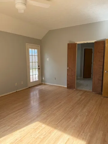 a view of an empty room with wooden floor and a window