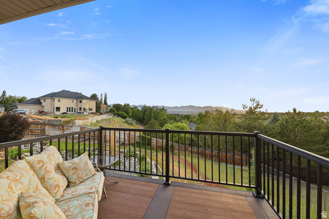 2342 Charros Road Sandy, UT 84092 - Photo 33 of 94 Composite decking with dark railing overlooking a verdant landscape and distant mountains