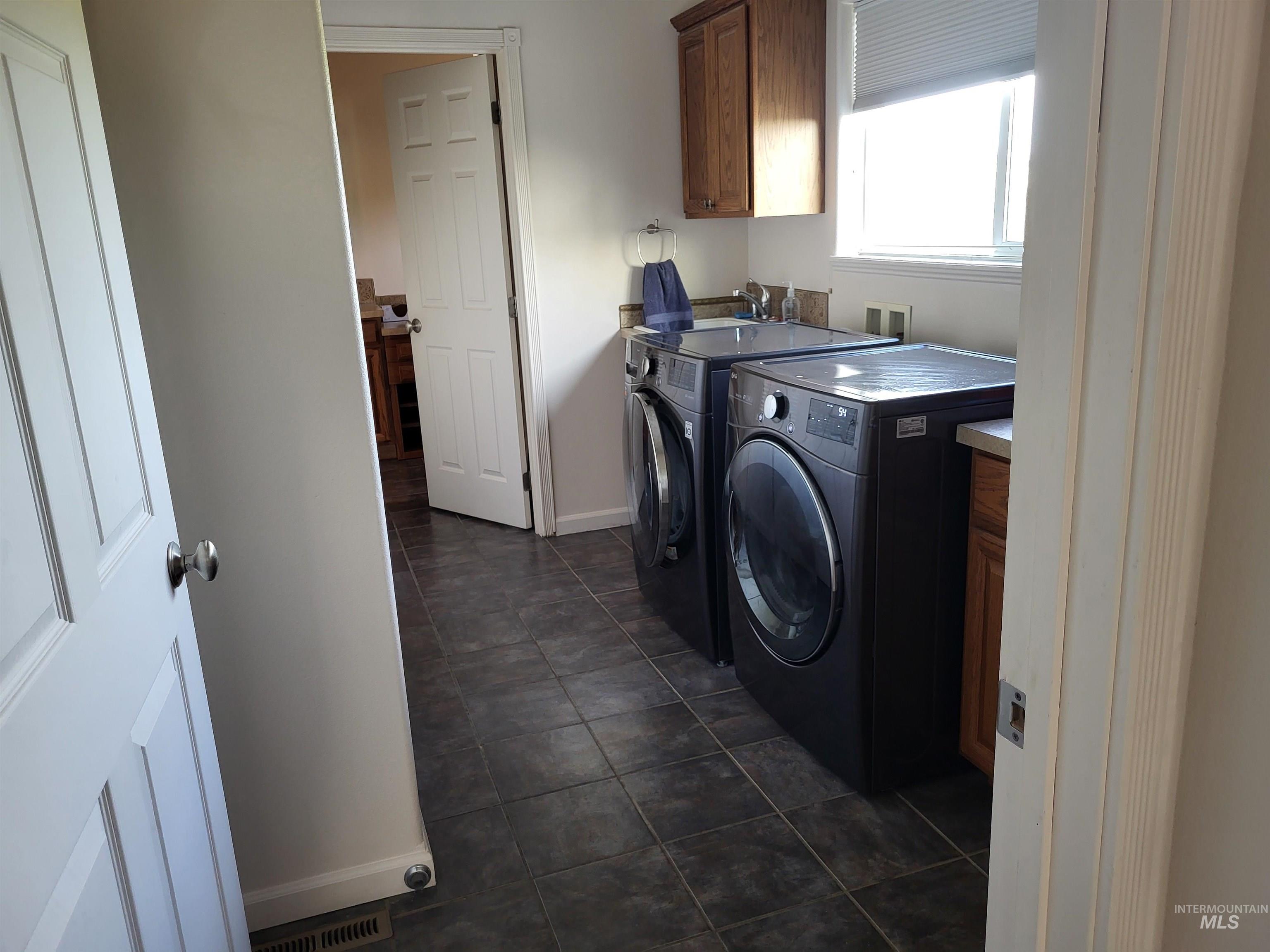 1085 Wallen Road Moscow, ID 83843 - Photo 28 of 50 Utility room featuring dark tile flooring, a window with horizontal blinds, and upper wood cabinetry