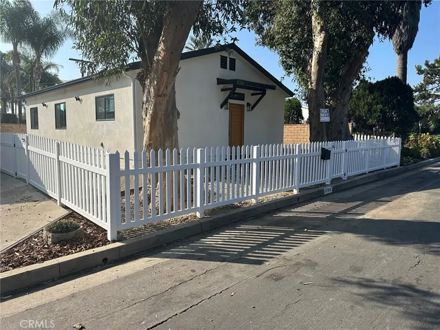 a view of a house with wooden fence next to a road