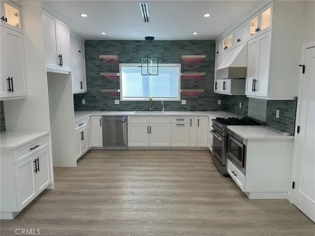 a large kitchen with stainless steel appliances granite countertop a stove top oven a sink and dishwasher