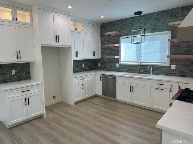 a kitchen with stainless steel appliances granite countertop a stove a sink and white cabinets