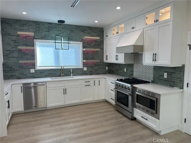 a kitchen with stainless steel appliances granite countertop a stove a sink and white cabinets