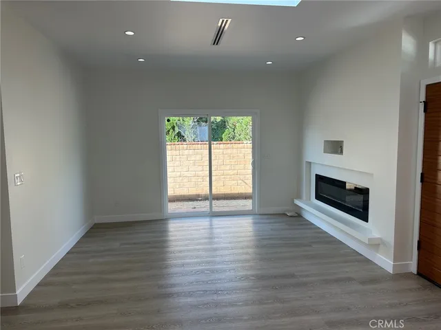 an empty room with wooden floor fireplace and windows