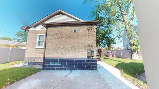 a view of a house with a yard plants and large tree