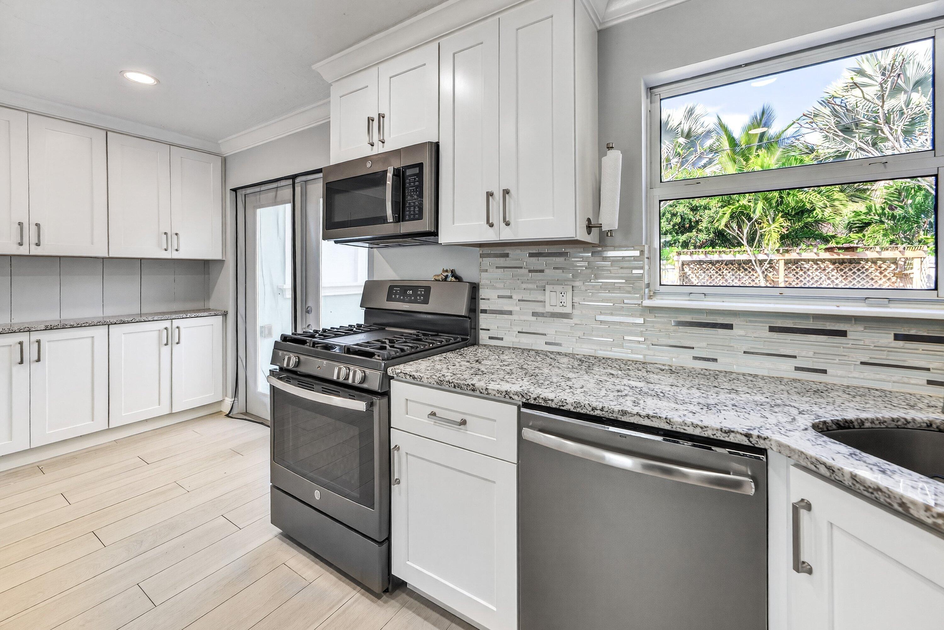 5565 Papaya Road Royal Palm Estates, FL 33413 - Photo 12 of 30 a kitchen with granite countertop white cabinets appliances a sink and a window