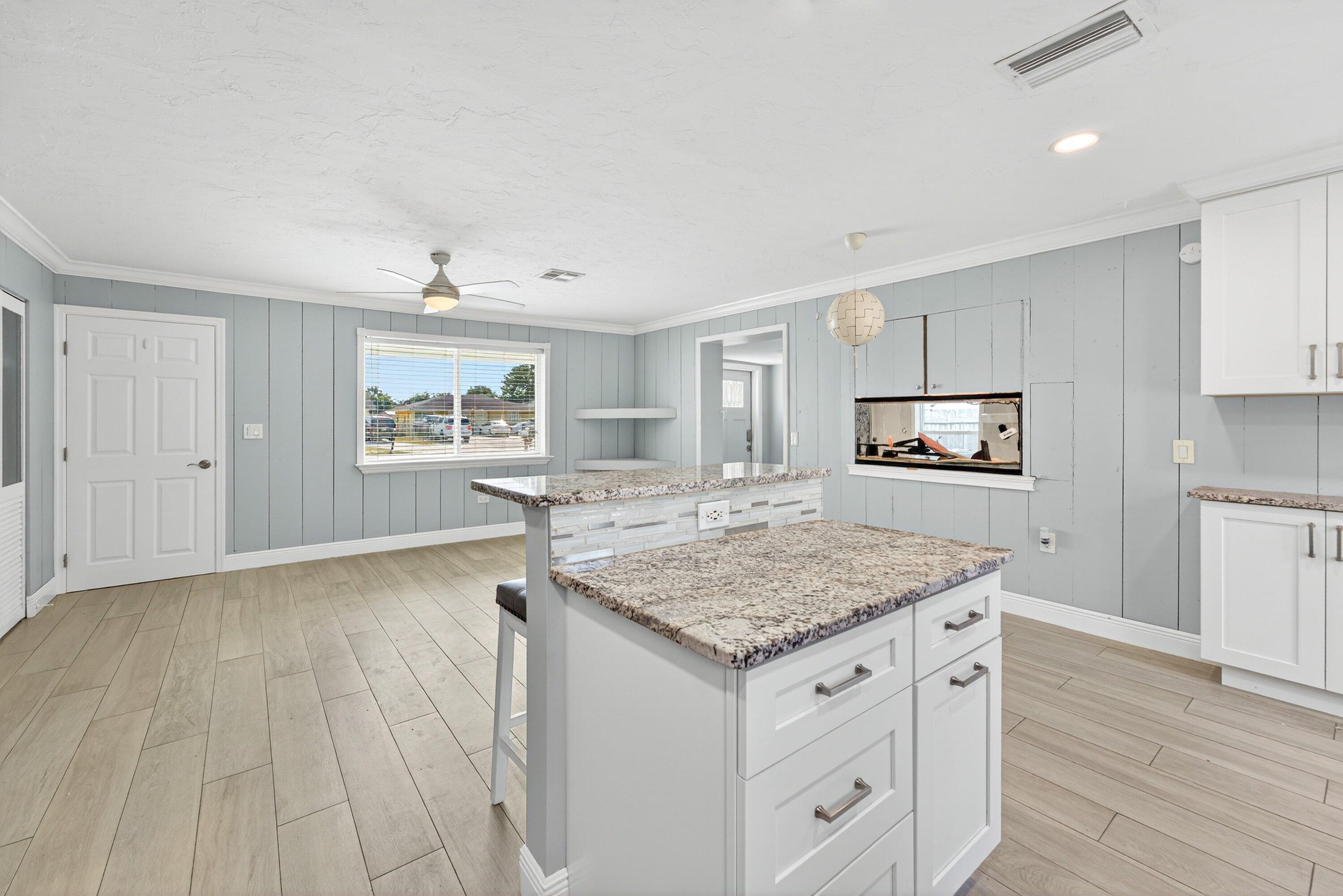 5565 Papaya Road Royal Palm Estates, FL 33413 - Photo 13 of 30 a kitchen with stainless steel appliances granite countertop a stove top oven a sink dishwasher and microwave with wooden floor