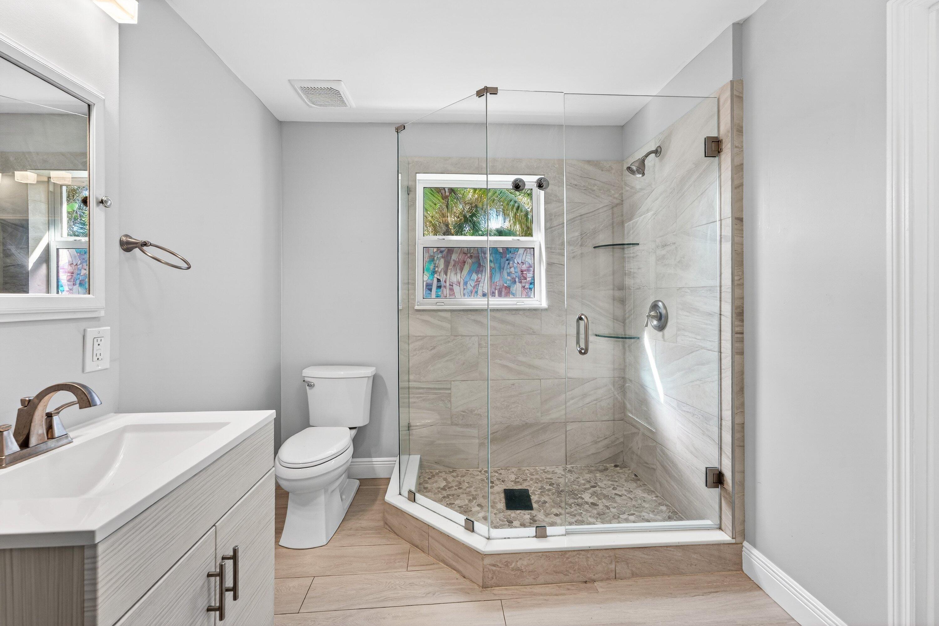 5565 Papaya Road Royal Palm Estates, FL 33413 - Photo 18 of 30 a bathroom with a granite countertop sink a mirror a toilet and shower