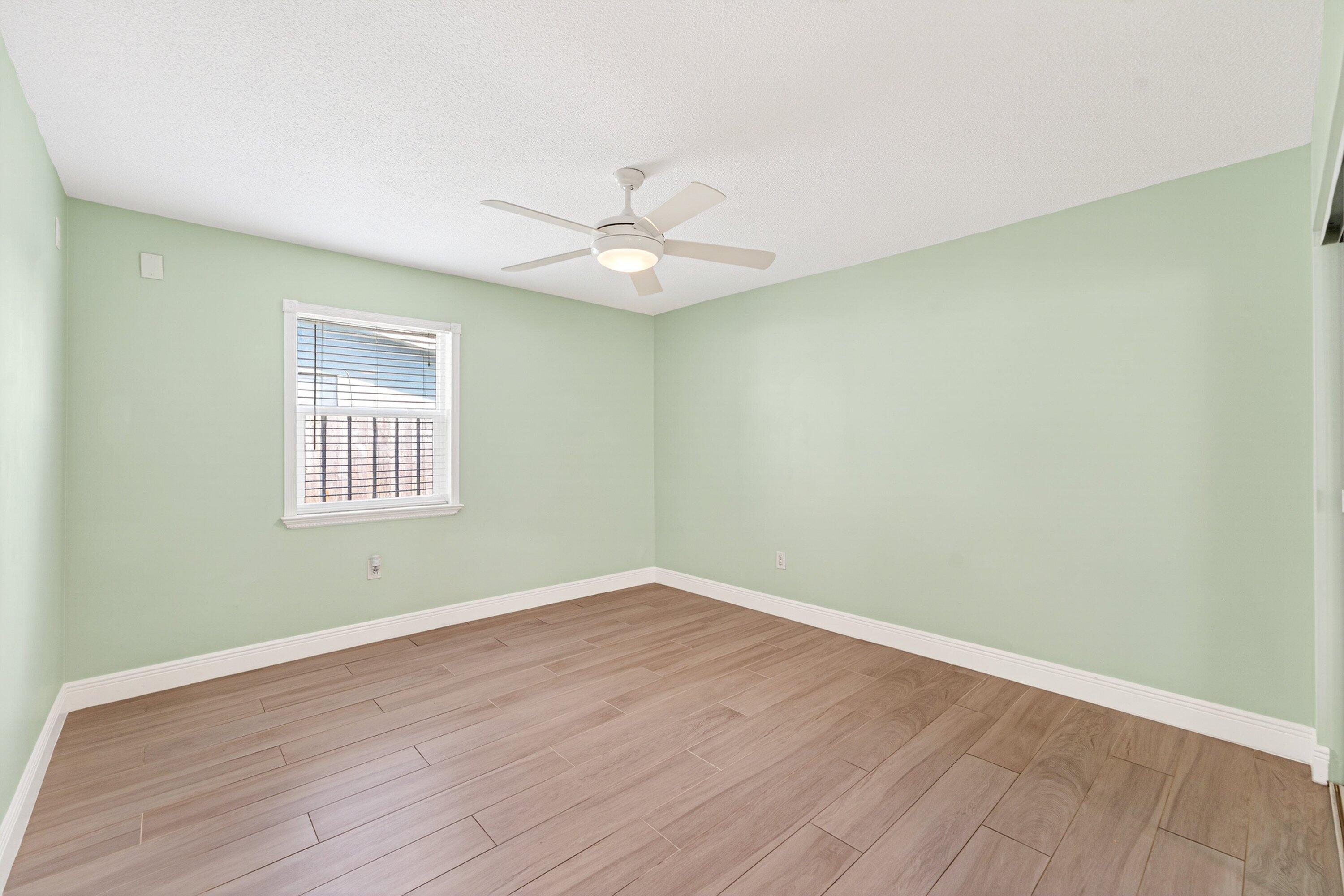 5565 Papaya Road Royal Palm Estates, FL 33413 - Photo 21 of 30 an empty room with wooden floor ceiling fan and window